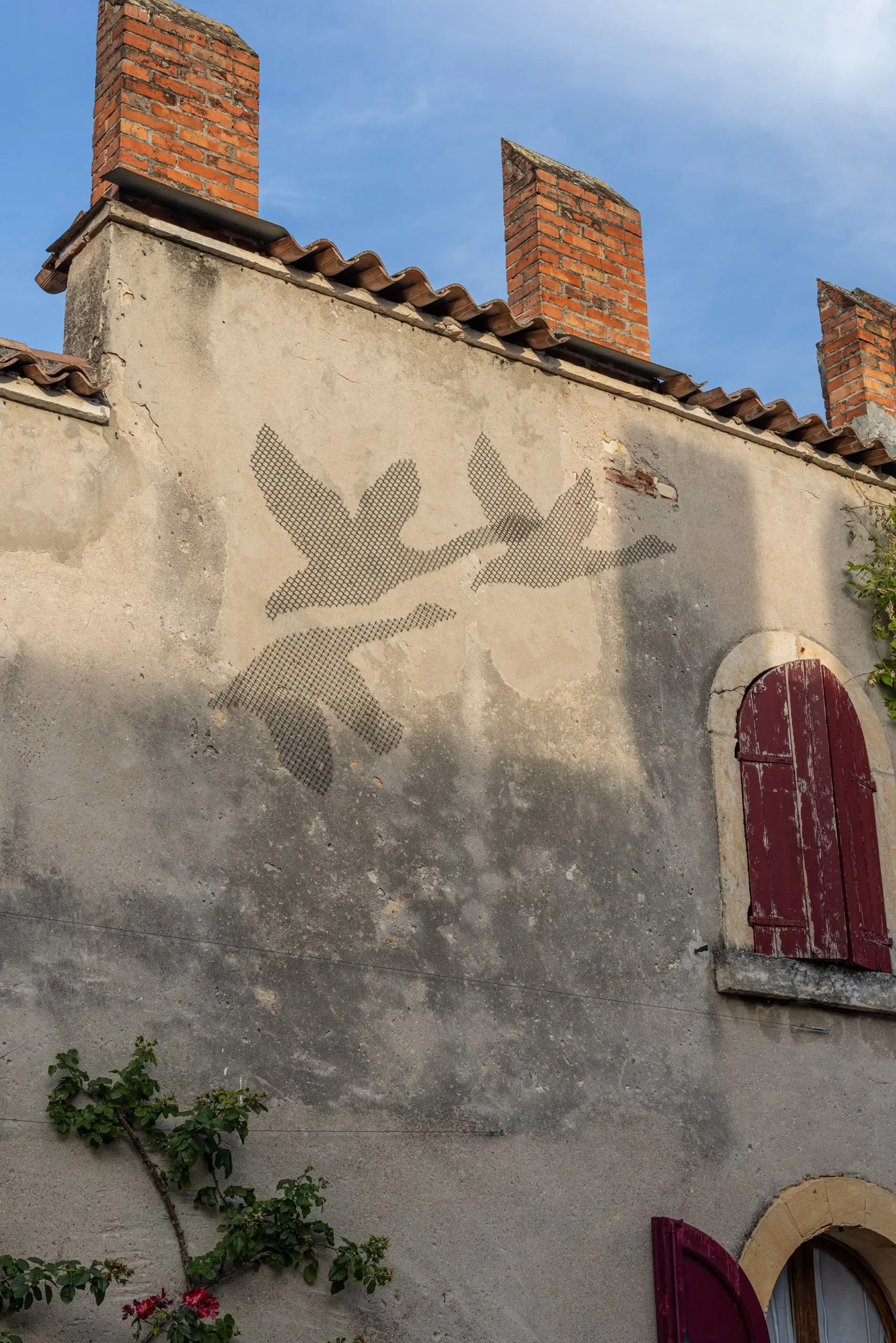 Facciata storica della Tenuta Fumanelli con decorazione di uccelli in volo e persiane rosse in legno.