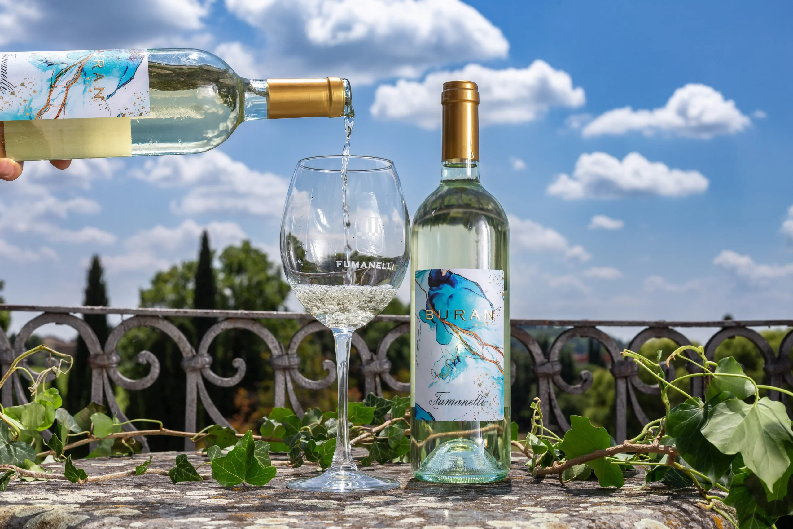 Vino bianco Buran Fumanelli servito all'aperto con sfondo naturale.