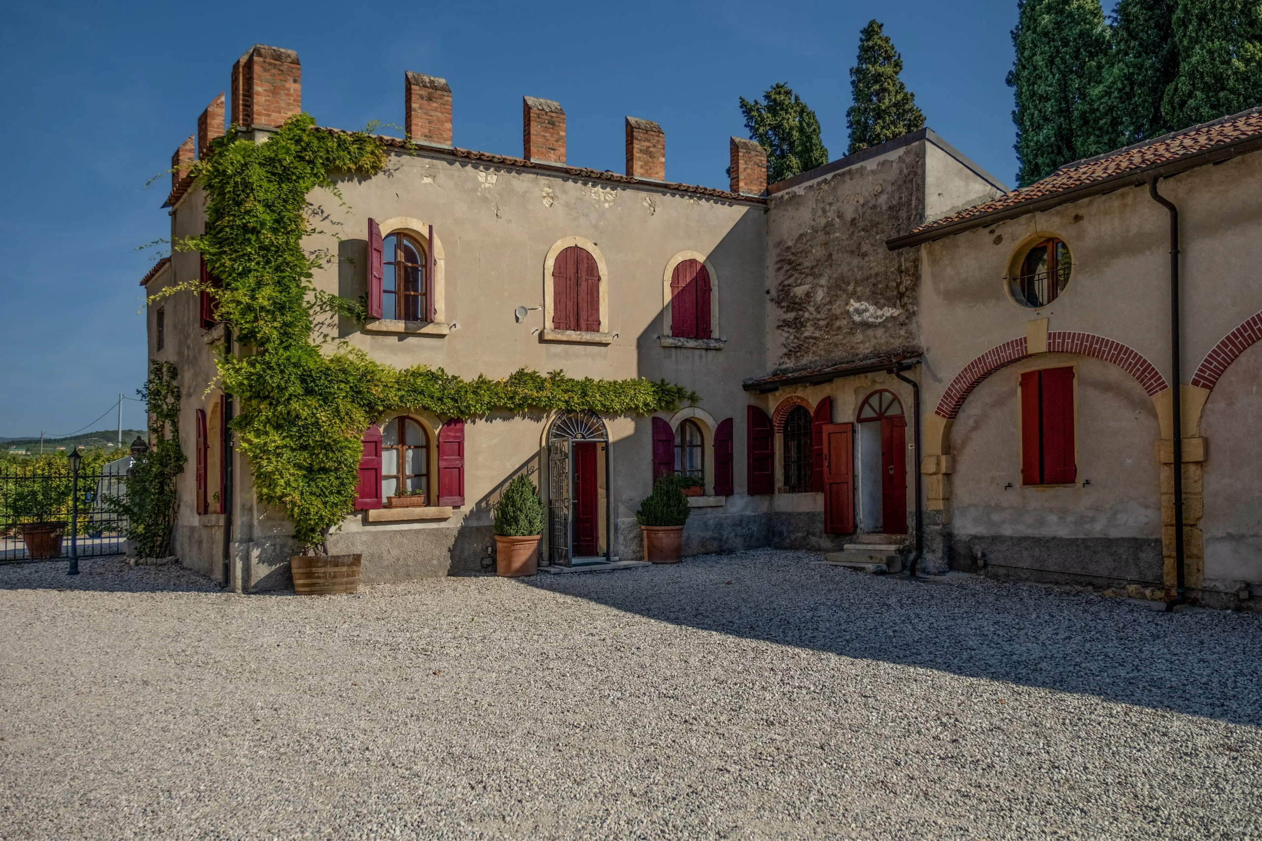 Dettaglio della corte interna di Villa Marchesi Fumanelli con finestre e porte rosse.