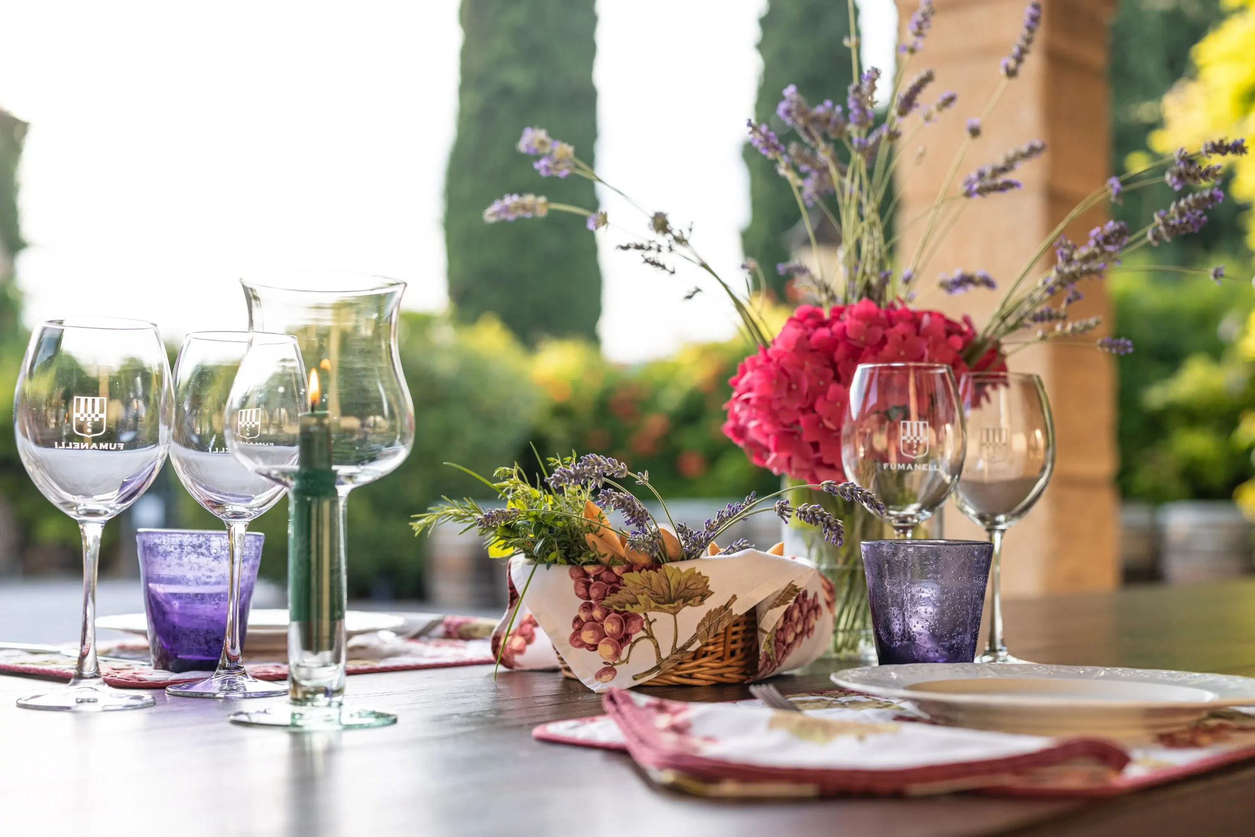 Tavola apparecchiata con calici Fumanelli, centrotavola floreale e dettagli eleganti per una degustazione all’aperto.