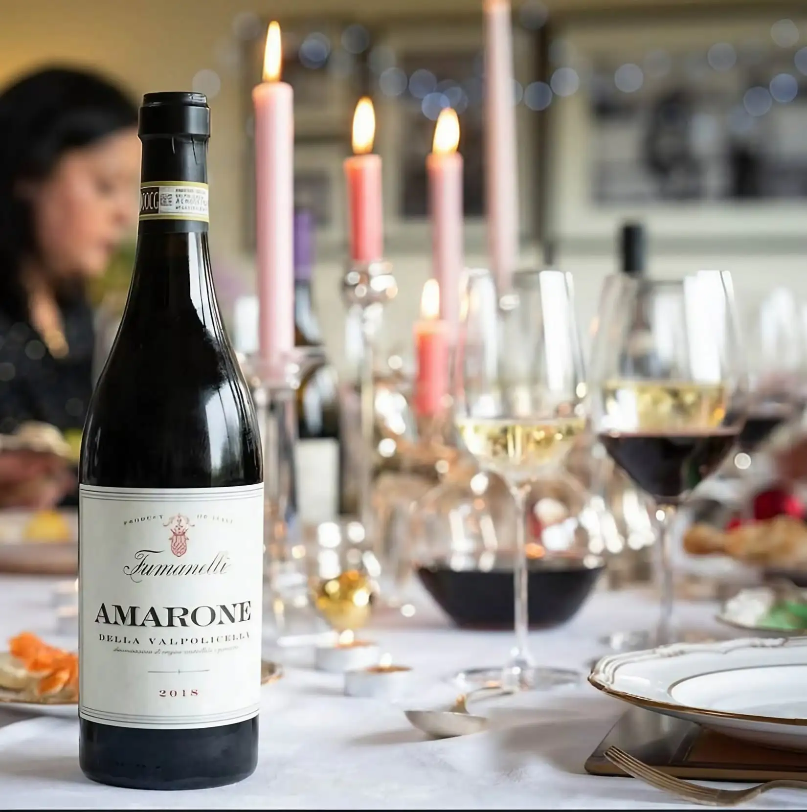 Bottiglia di Amarone della Valpolicella Fumanelli su tavola elegante con calici di vino e candele accese.