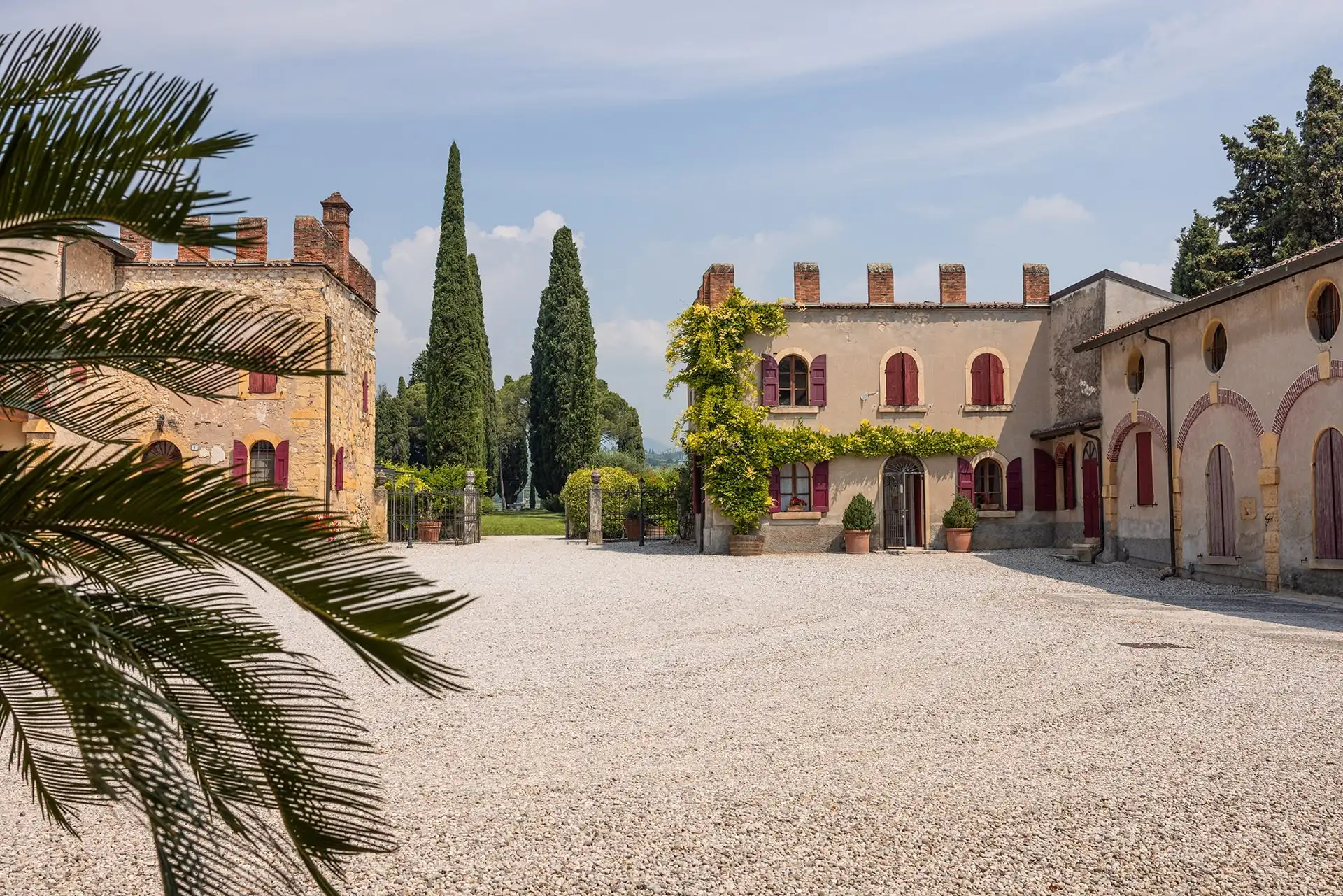 Corte interna della villa Marchesi Fumanelli con edifici storici e cipressi sullo sfondo.