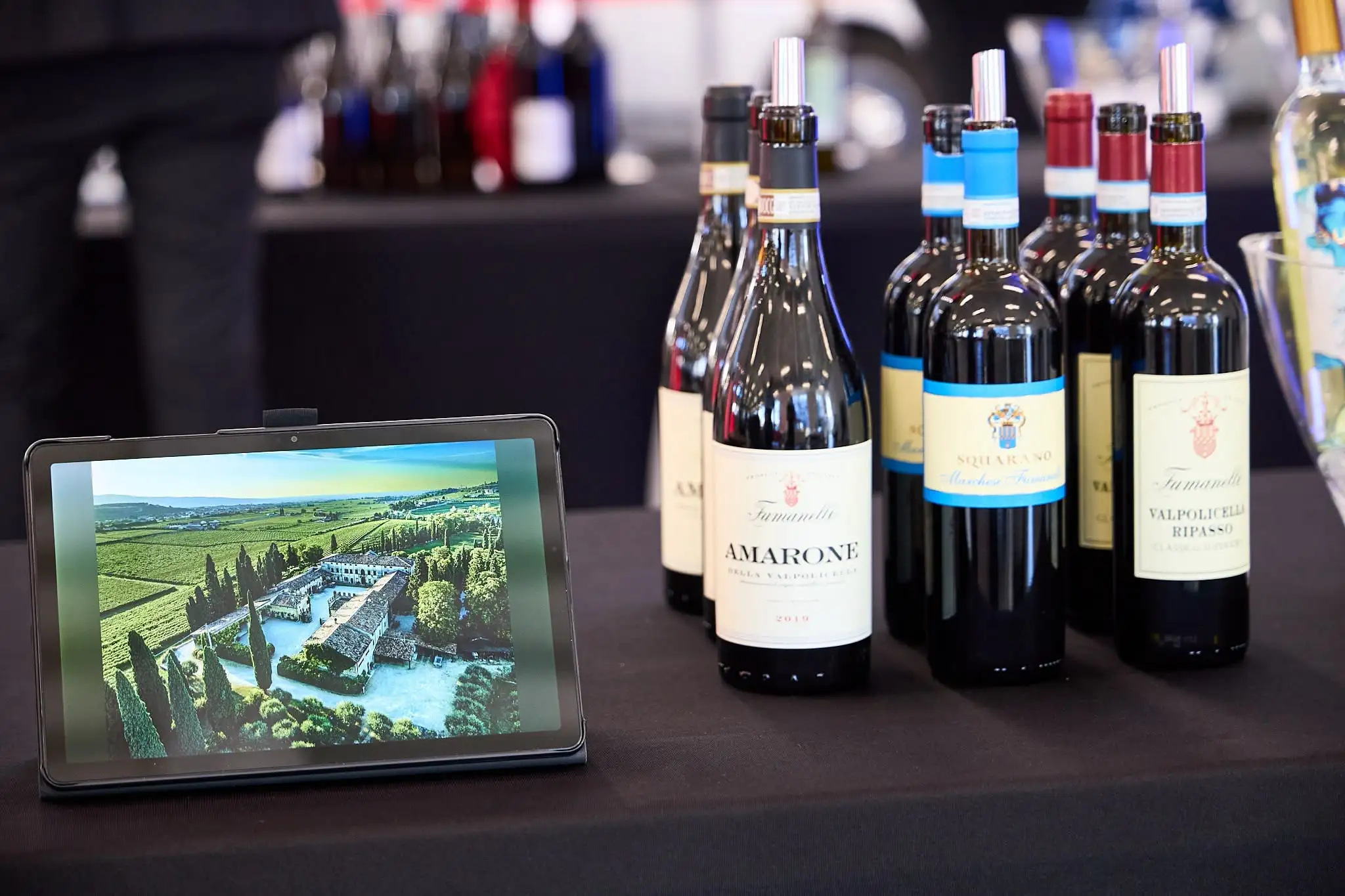 Esposizione vini Fumanelli con tablet che mostra la villa e i vigneti